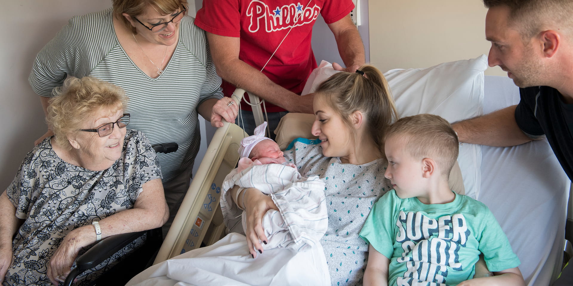 Family surrounding mother with newborn in hospital | Doylestown Health