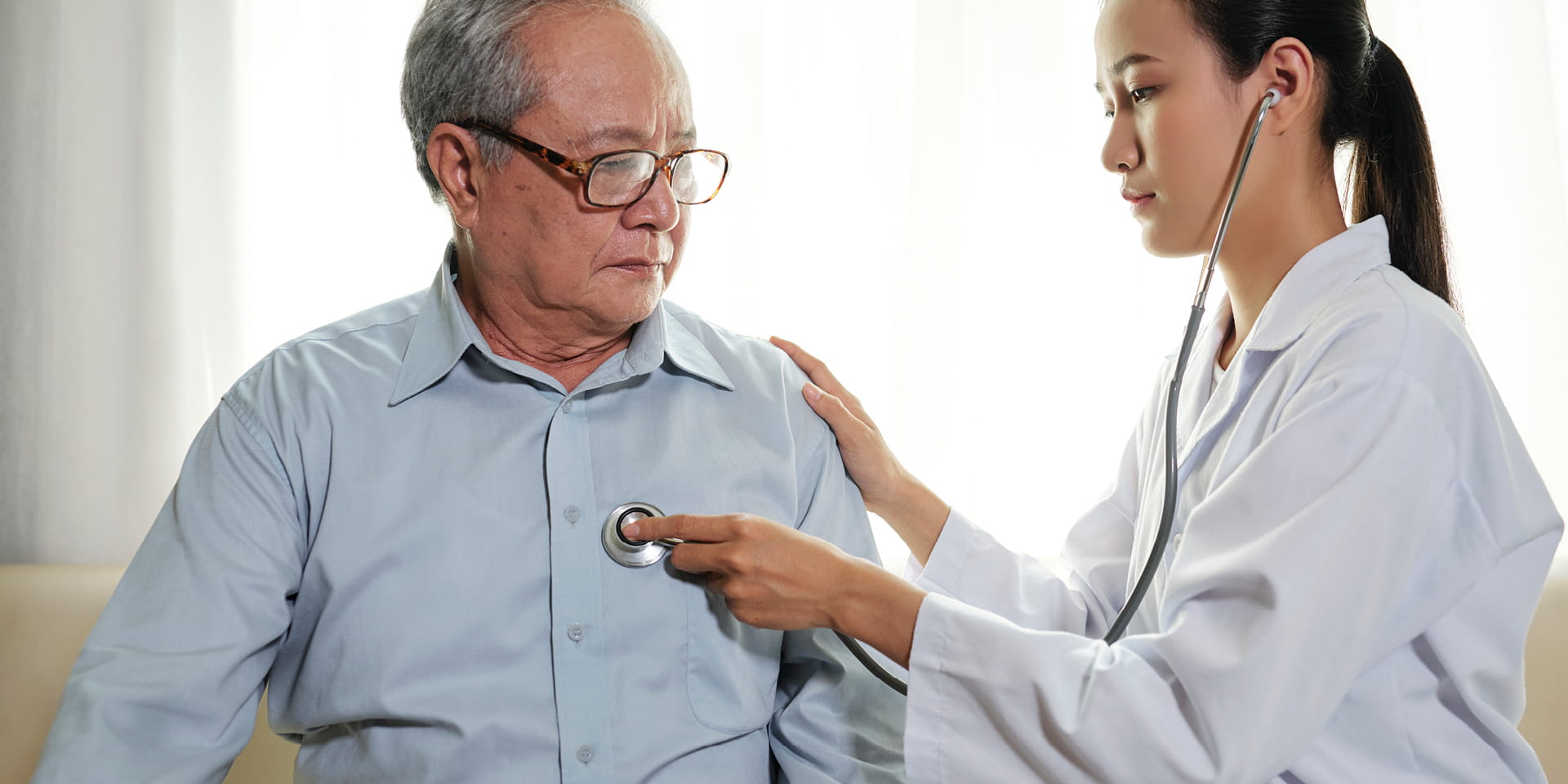 Doctor listening to man's heart